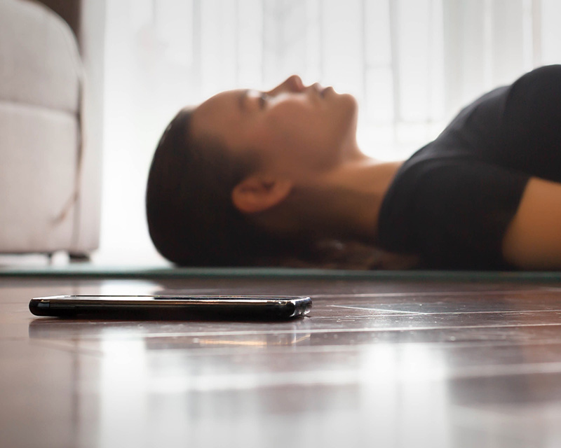 Woman next to a phone doing a guided meditation group in Valley Stream